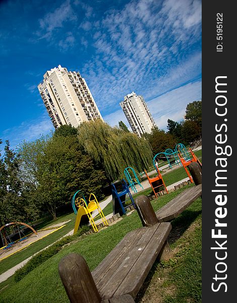 A colorful playground in a park, shot in front of two skyscrapers and a very deep blue sky. A colorful playground in a park, shot in front of two skyscrapers and a very deep blue sky.