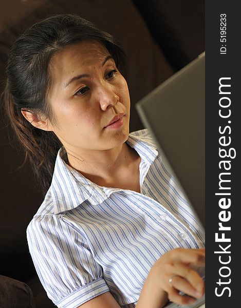 An asian lady using a laptop to do her work. An asian lady using a laptop to do her work