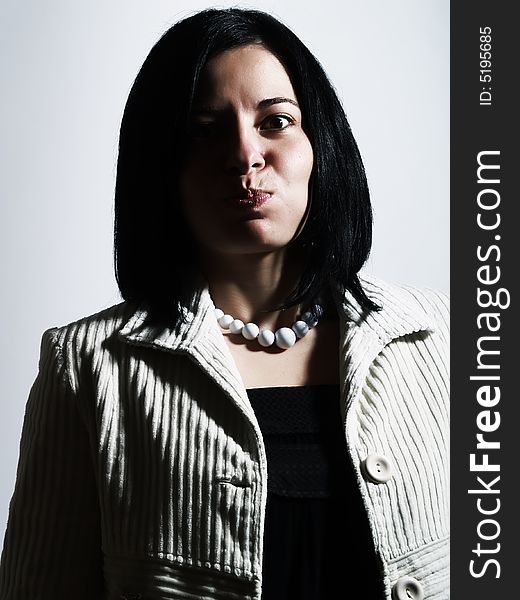 A high-key portrait about an attractive lady with black hair who is looking ahead, she is bulging out her cheeks and she is pouting. She is wearing a white coat, a black dress, and a white necklace. A high-key portrait about an attractive lady with black hair who is looking ahead, she is bulging out her cheeks and she is pouting. She is wearing a white coat, a black dress, and a white necklace.