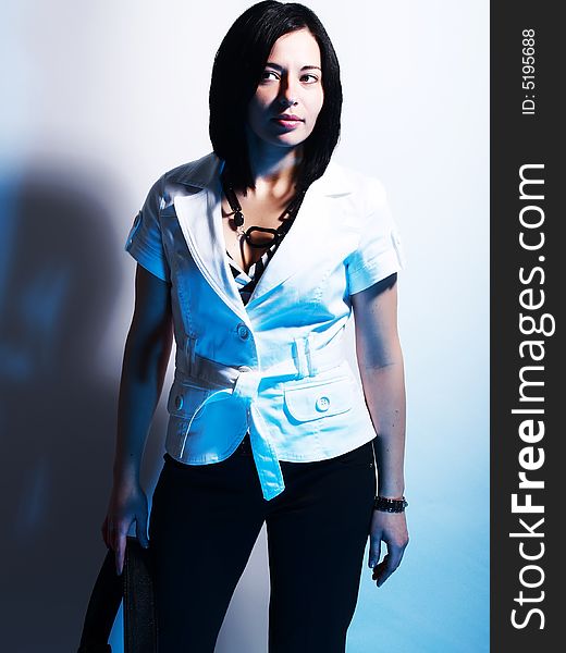 A high-key portrait about a cute stylish lady with black hair who is lighted with blue and she has an attractive look. She is wearing black pants, a white coat and a stylish handbag. A high-key portrait about a cute stylish lady with black hair who is lighted with blue and she has an attractive look. She is wearing black pants, a white coat and a stylish handbag.