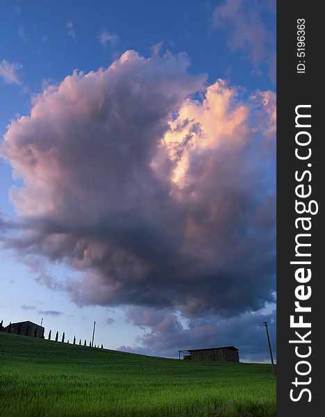 Evening clouds above grassy fields in the Tuscany region of Italy.