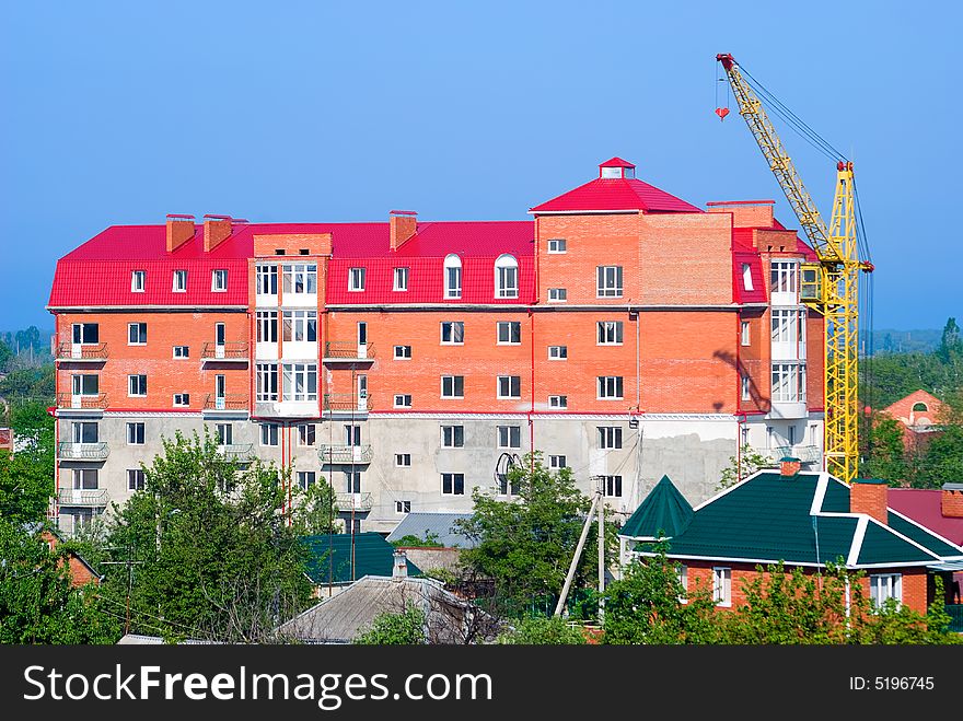 The building crane stands near a abuilding house. The building crane stands near a abuilding house