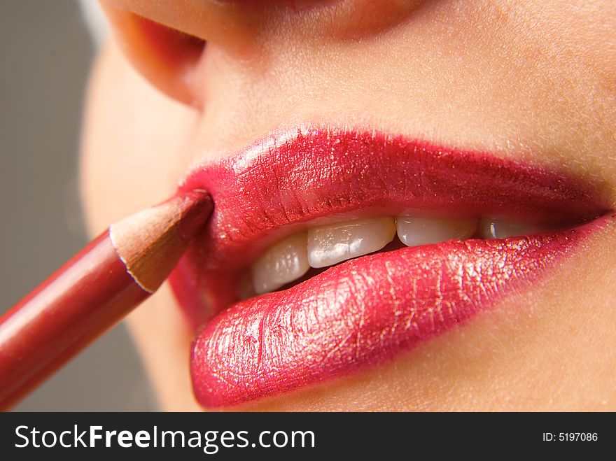 Applying cosmetics on the beautiful woman's lips. Applying cosmetics on the beautiful woman's lips