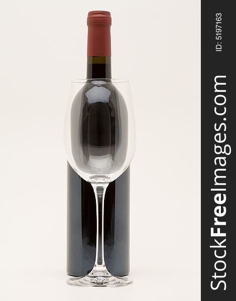 Isolated red wine bottle with empty glass in front