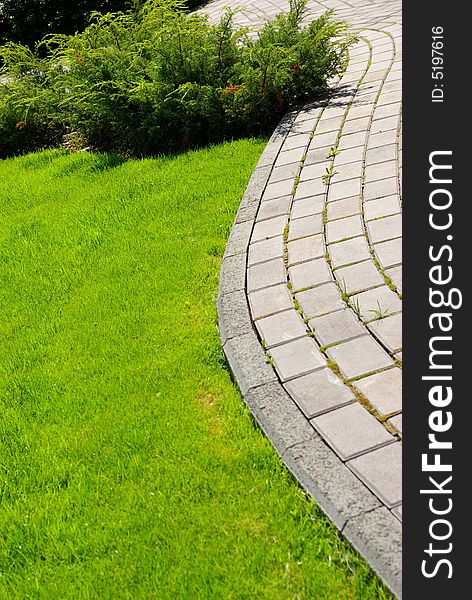 Garden stone path with grass growing up between the stones