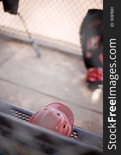 Baseball helmet and bats sitting outside on a bench against the bench during a baseball game