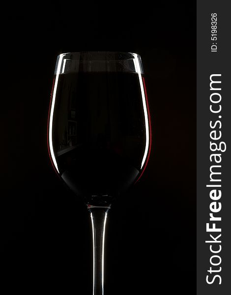 Red wineglass on a black background with rim light. Red wineglass on a black background with rim light