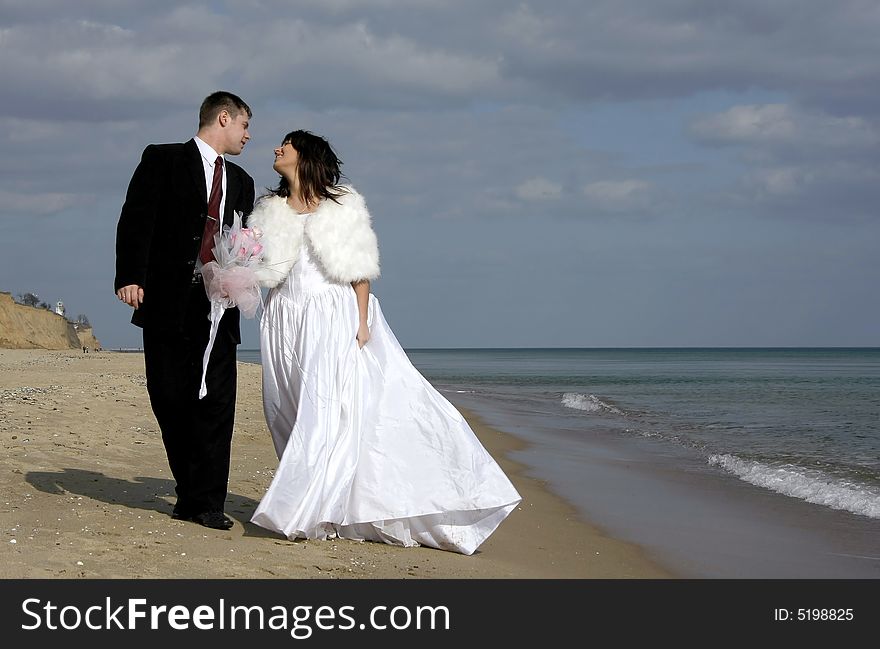 Two lovers, walk on the beach near the sea, loving look at each other. Two lovers, walk on the beach near the sea, loving look at each other