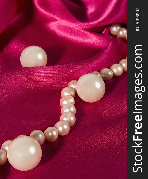 Pink pearl necklace on a violet silk.