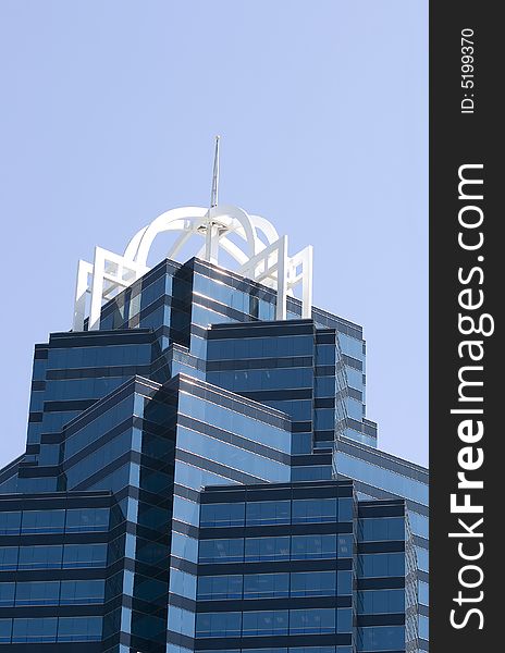 Top of a modern blue glass office tower against blue sky. Top of a modern blue glass office tower against blue sky