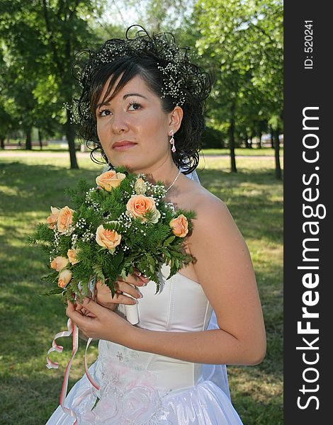 Bride with bouquet from roses looks upwards. Bride with bouquet from roses looks upwards