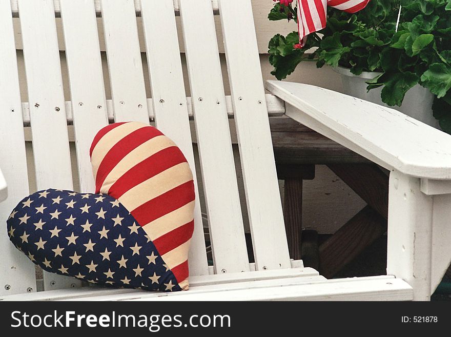 An american flag pillow sitting in an adirondack chair. An american flag pillow sitting in an adirondack chair.