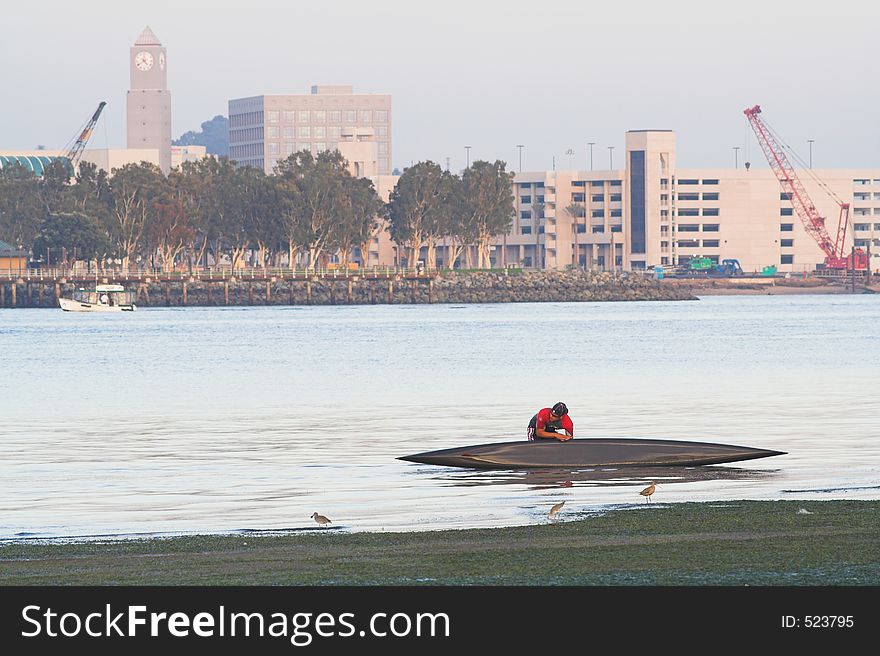 Canoer wrestles canoe out of the water after paddling on San Diego Bay. (Coronado, CA). Canoer wrestles canoe out of the water after paddling on San Diego Bay. (Coronado, CA)