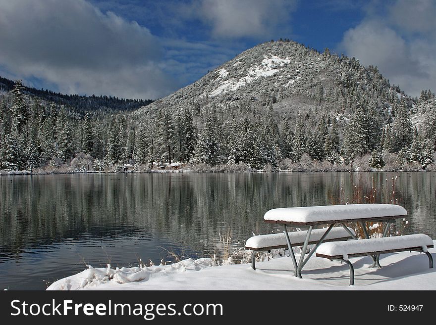 Fresh snow covers picnic table near mountain lake in the Southern Sierras. Fresh snow covers picnic table near mountain lake in the Southern Sierras