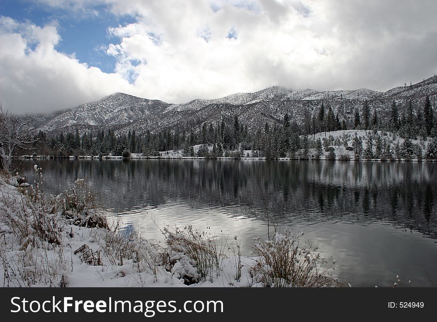Winter clouds and snow on mountains reflected in mountain lake. Winter clouds and snow on mountains reflected in mountain lake