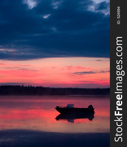 A fishing boat stands moored in shallow water on a quiet morning before sunrise. A fishing boat stands moored in shallow water on a quiet morning before sunrise.