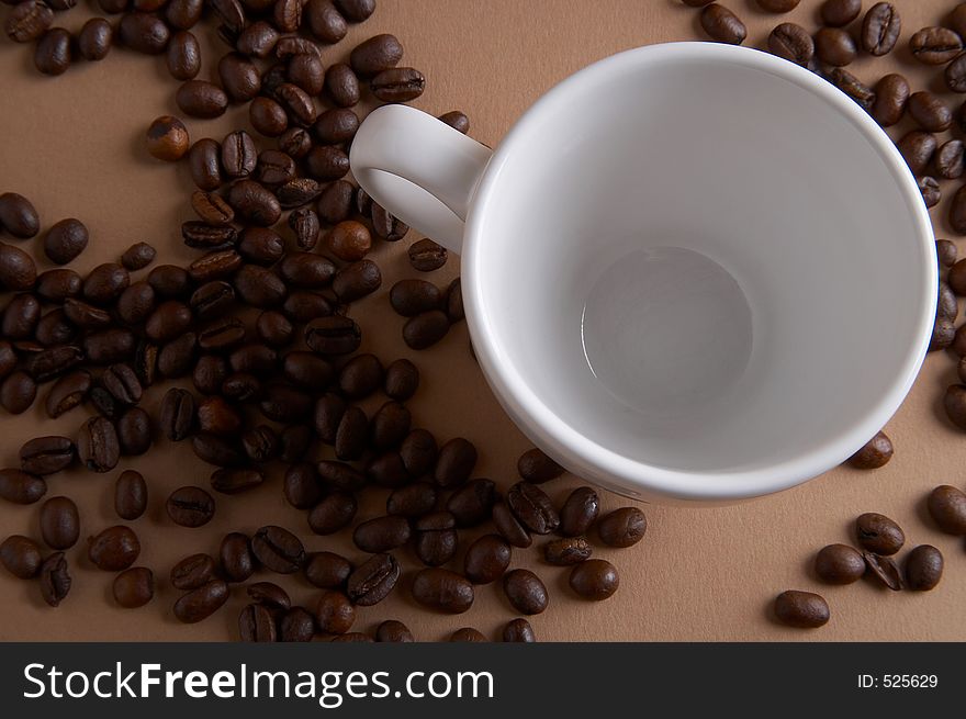 Coffe cup with coffee beans on brown background - Kaffeetasse mit Kaffeebohnen vor braunem Hintergrund. Coffe cup with coffee beans on brown background - Kaffeetasse mit Kaffeebohnen vor braunem Hintergrund