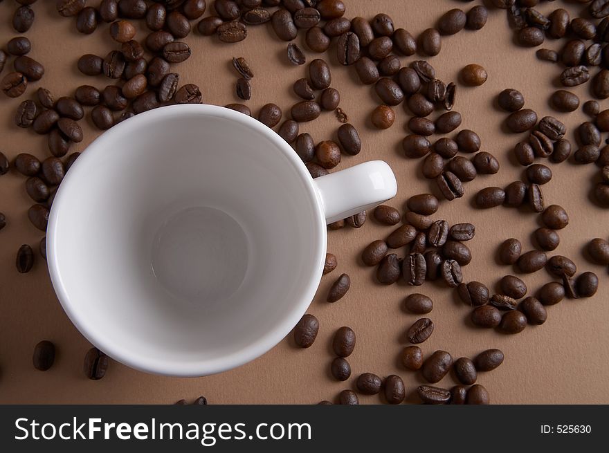 Coffe cup with coffee beans on brown background - Kaffeetasse mit Kaffeebohnen vor braunem Hintergrund. Coffe cup with coffee beans on brown background - Kaffeetasse mit Kaffeebohnen vor braunem Hintergrund