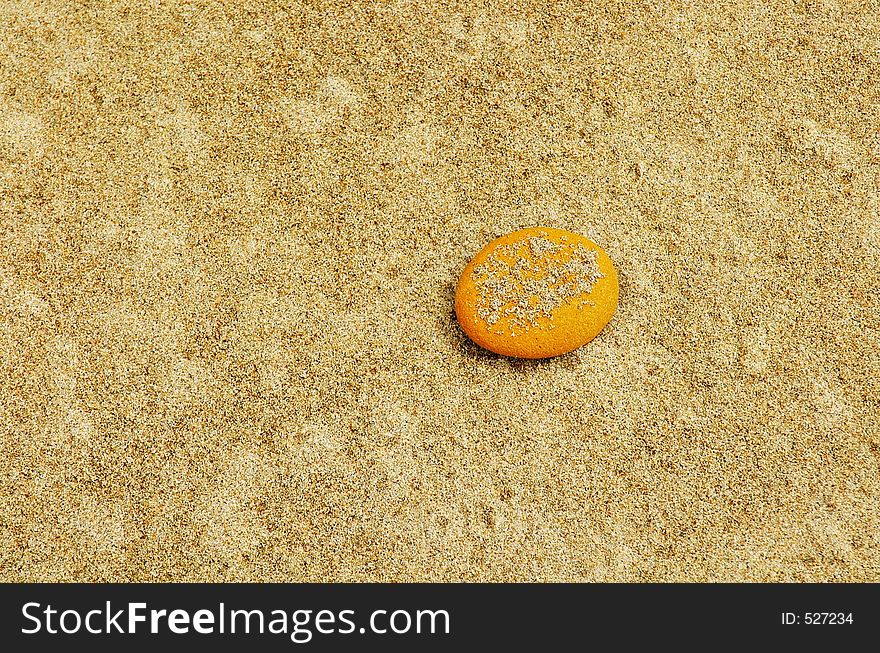 A lone bright yellow pebble washed up on a beach with coarse, natural sand. A lone bright yellow pebble washed up on a beach with coarse, natural sand.