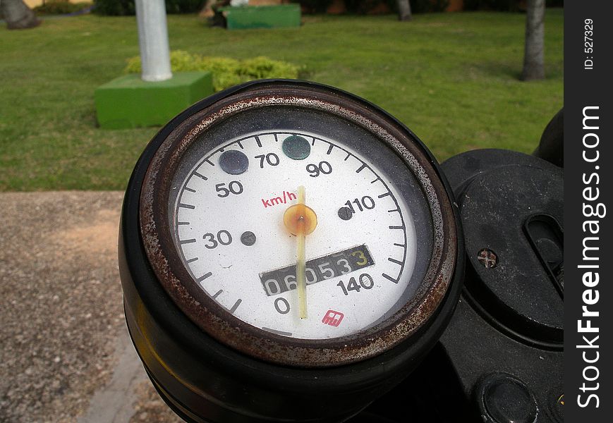 Old rusted speedometer on an old motorcycle. Focus on the speedometer, shallow depth of field.