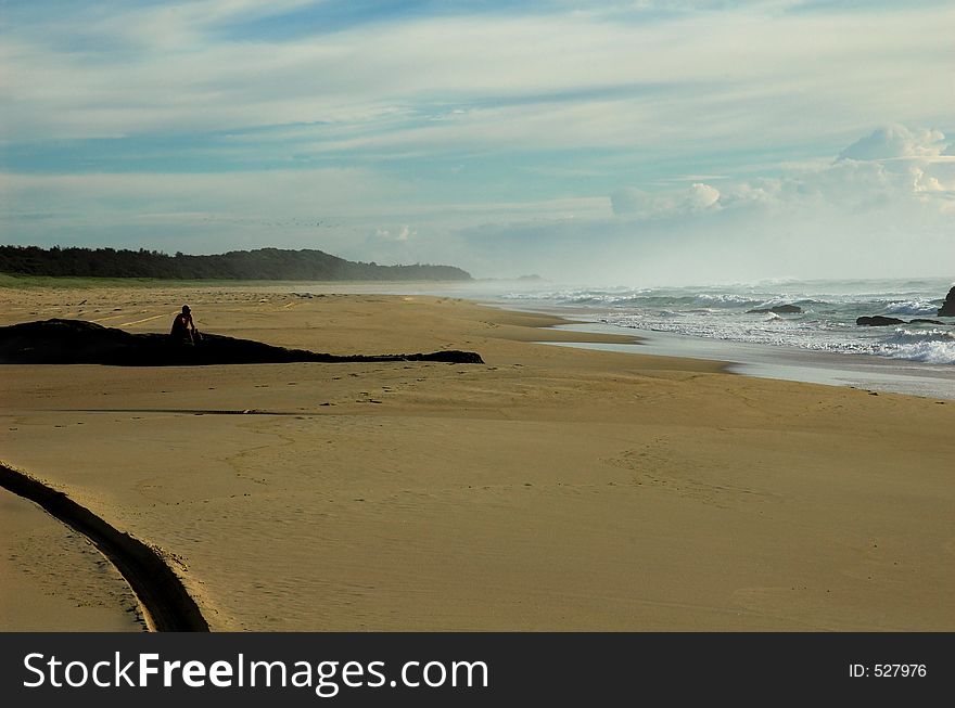 Lone man sitting on the beach in the early morning. Lone man sitting on the beach in the early morning