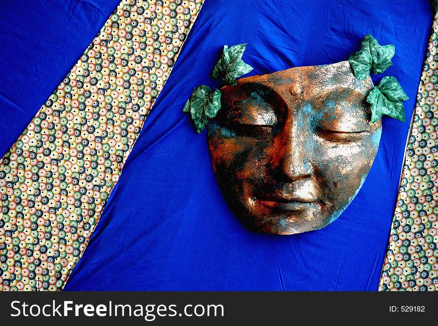 Copper mask with leaves on hand made quilt