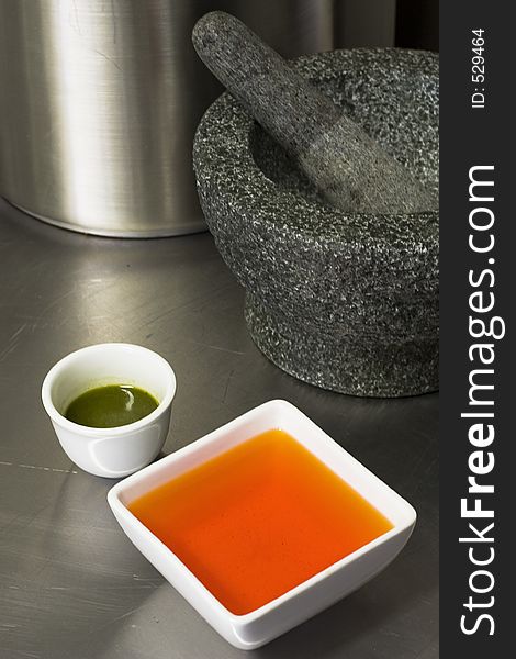 Sauces infront of a morter & pestle. Kitchen setting.
