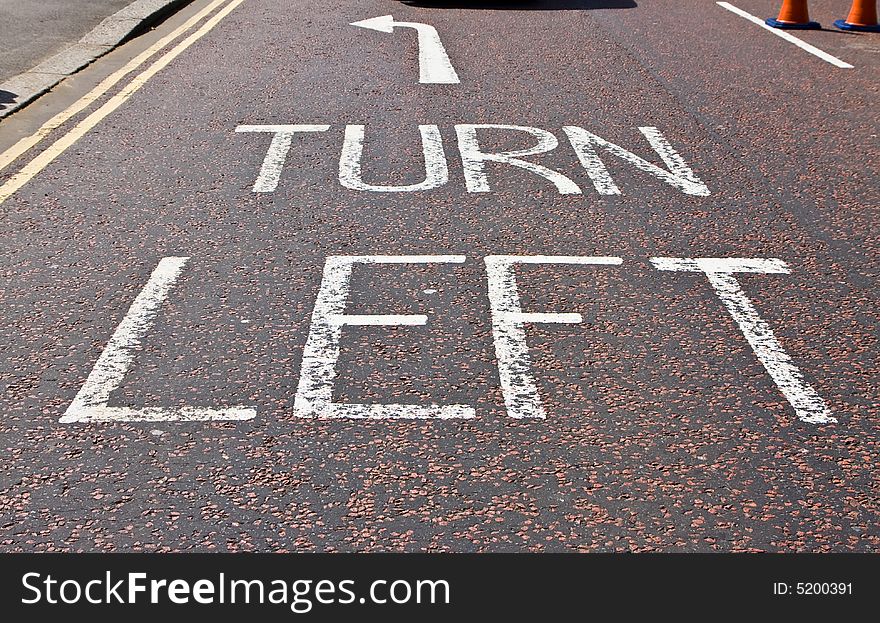 Turn left sign in typical London street asphalt