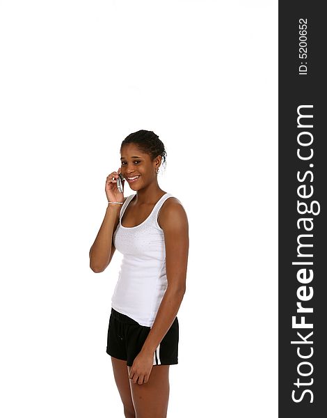 Pretty African American teenage girl wearing athletic shorts and a tank top, talking on a cell phone. Pretty African American teenage girl wearing athletic shorts and a tank top, talking on a cell phone.