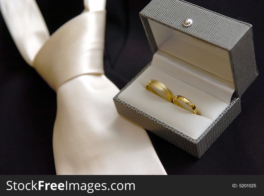 Close up photo of Wedding rings & wedding tie
