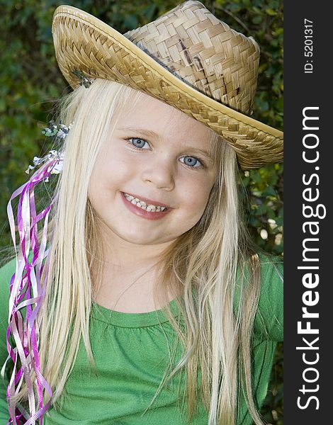 A little girl in a hat and green t-shirt with ribbons in her hair