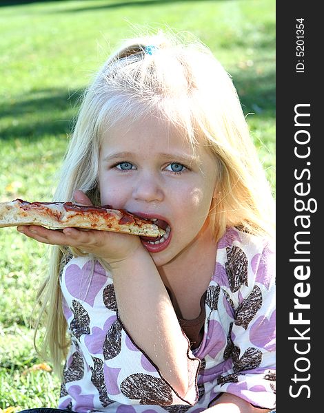 A little girl eating pizza slice