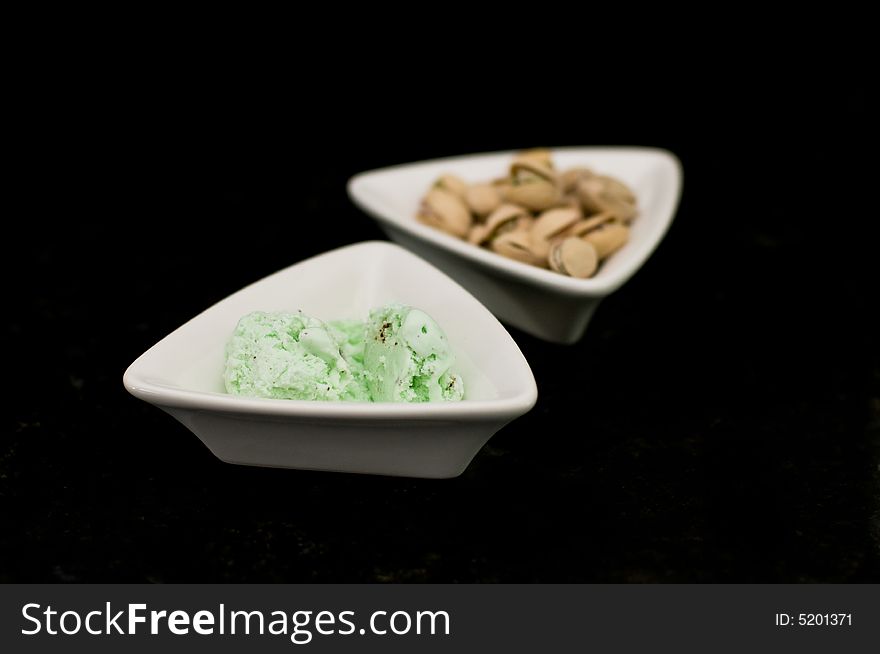 Small dish of pistachio ice cream with dish of pistachios. Small dish of pistachio ice cream with dish of pistachios