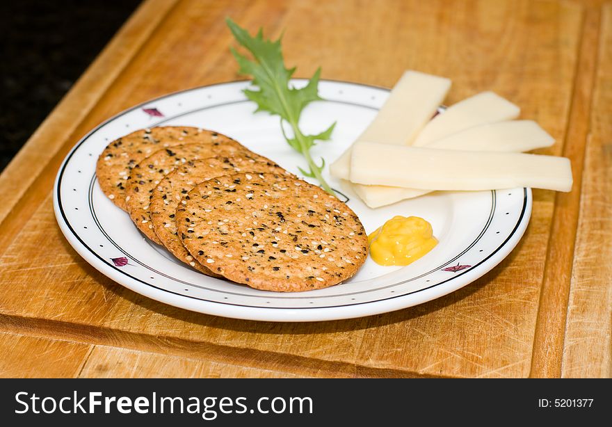 Plate of crackers and cheese with mustard and garnish. Plate of crackers and cheese with mustard and garnish