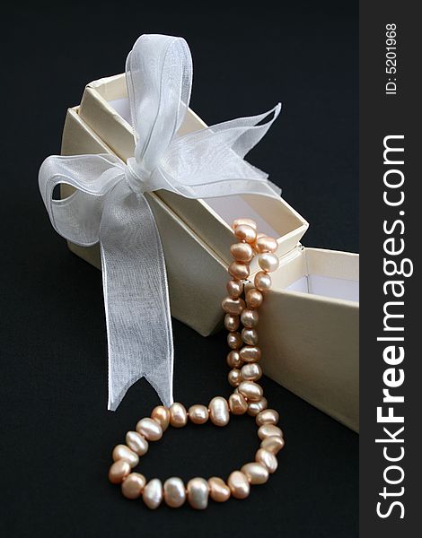 Small cream colored box with ribbon and pearl necklace