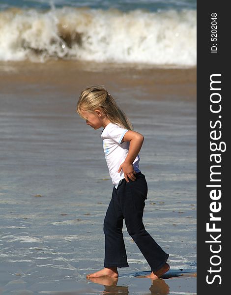 A white caucasian girl child walking alone on the beach. A white caucasian girl child walking alone on the beach