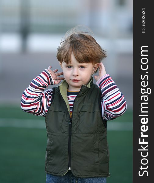 The cheerful kid on a green field of stadium