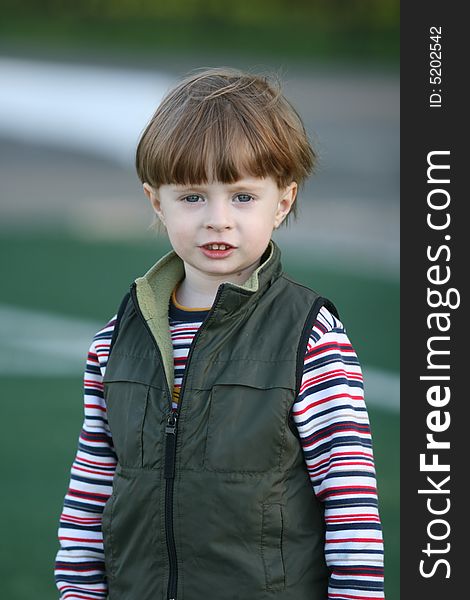 The cheerful kid on a green field of stadium