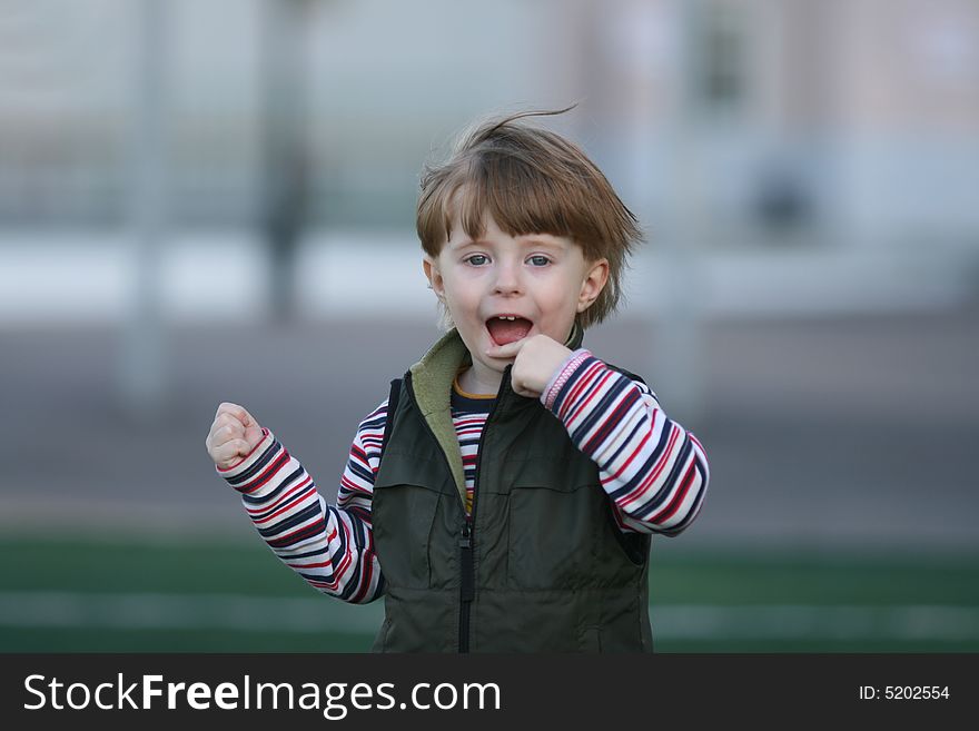 The cheerful kid on a green field of stadium