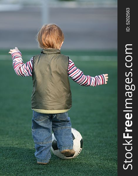 The little boy playing football in stadium. The little boy playing football in stadium