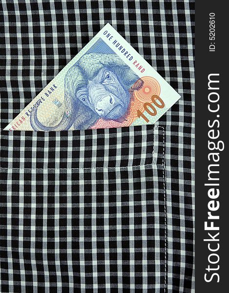 South African Rand banknote in the pocket of a casual garment.  Photographed in a studio.