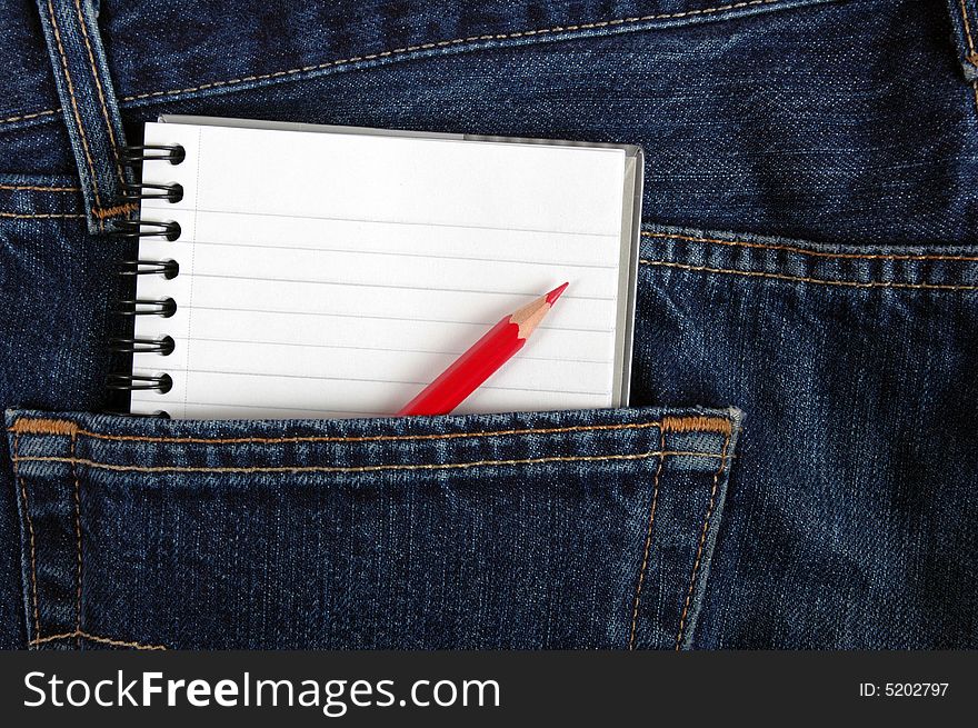 A notebook and pencil in the back pocket of denim trousers. A notebook and pencil in the back pocket of denim trousers.