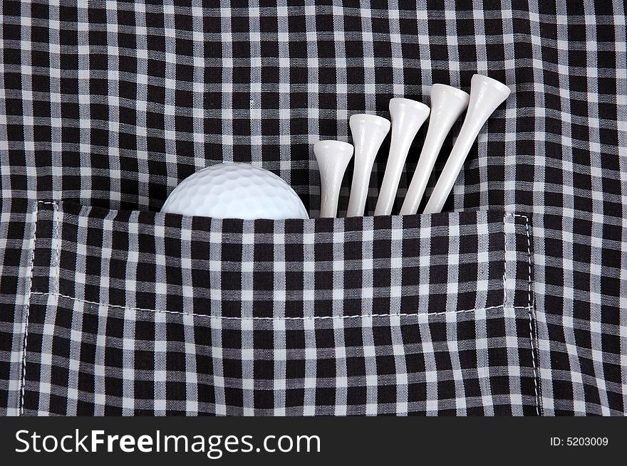 A Golf Ball and a number of tees in the pocket of a checkered shirt. A Golf Ball and a number of tees in the pocket of a checkered shirt.