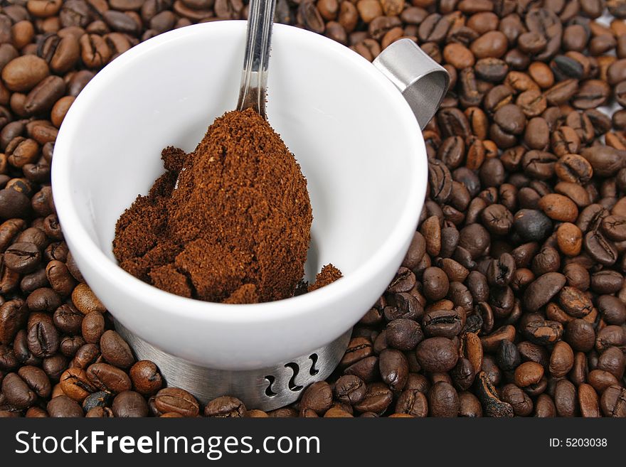 Coffee, spoon and white cup on coffee beans background. Coffee, spoon and white cup on coffee beans background