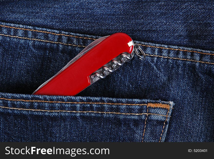 A red pocket knife in the pocket of denim trousers. A red pocket knife in the pocket of denim trousers.