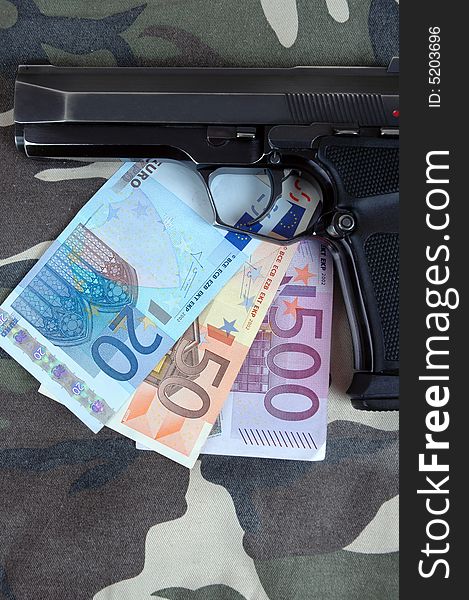 A pistol with an amount of Euros included in the photo.  Photographed in a studio.