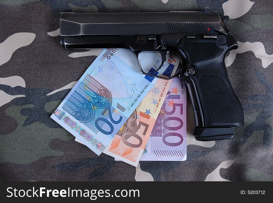 A pistol with an amount of Euros included in the photo.  Photographed in a studio.