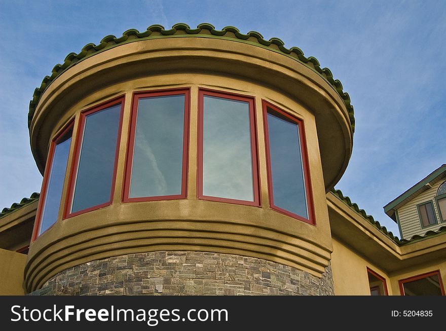 A round turret of windows reflects a morning sky with a thin veneer of clouds. A round turret of windows reflects a morning sky with a thin veneer of clouds.