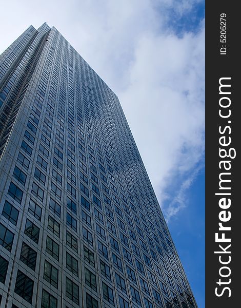 Looking up a very tall steel office building with cloudy sky