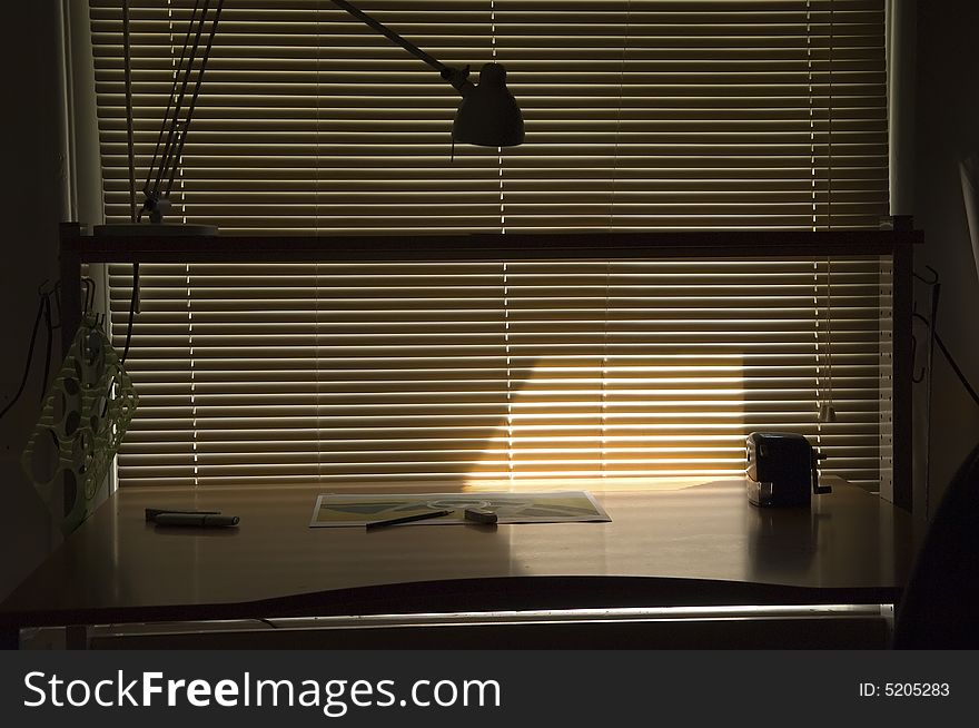 A drawing desk located by the windows with the blinds closed. A drawing desk located by the windows with the blinds closed.